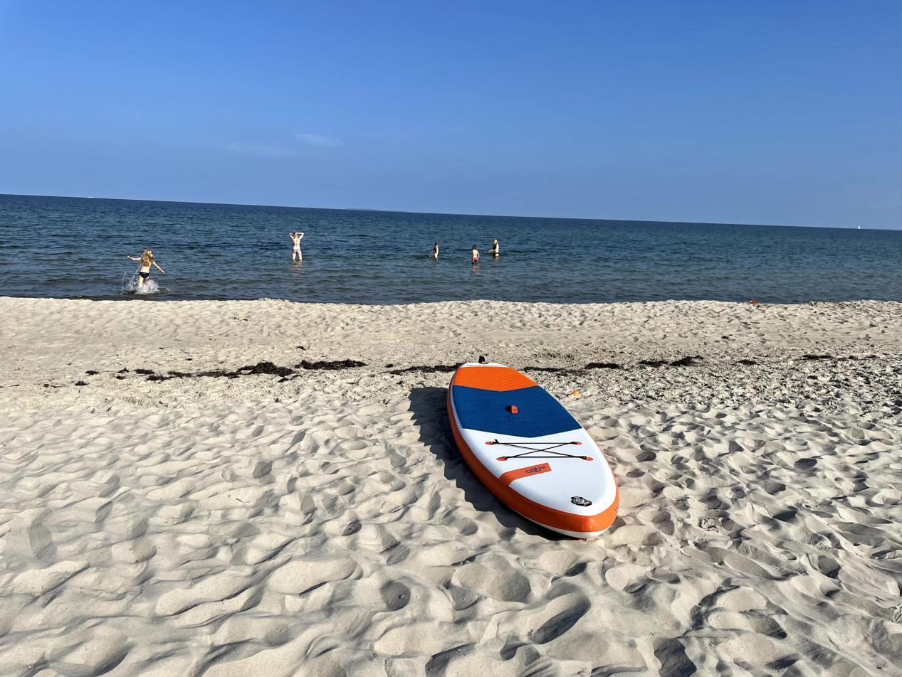 SUP-Board im Sand am Südstrand, im Wasser Badende